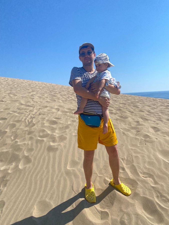 Levent Kutlu holding his child on a coastal sand dune