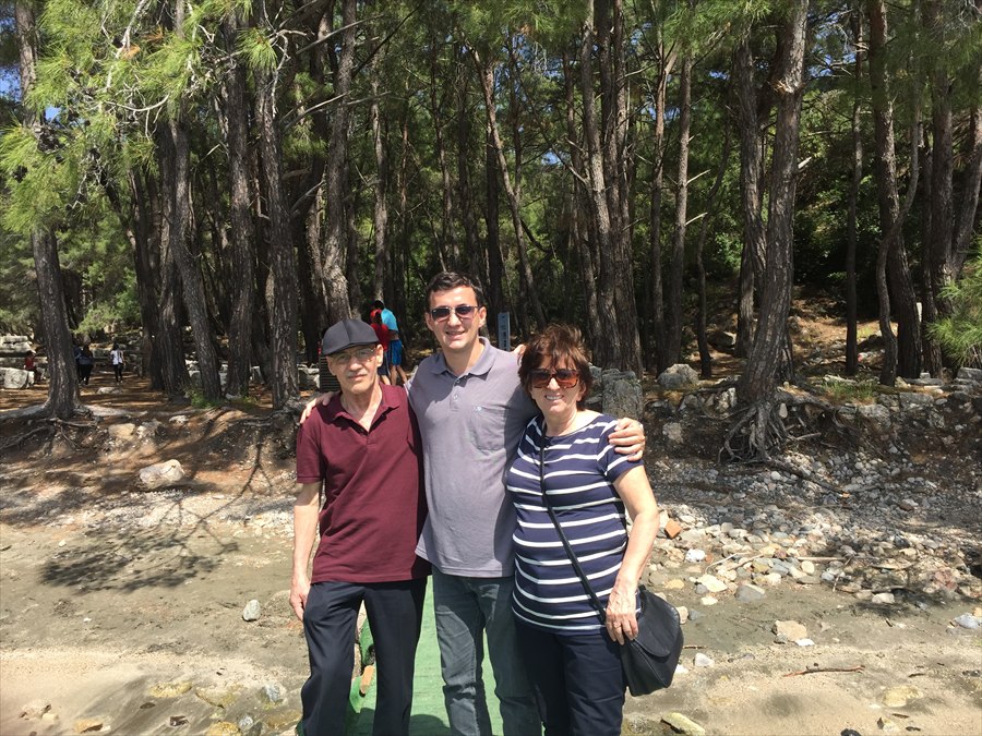 Levent Kutlu standing with his father and mother in a wooded setting